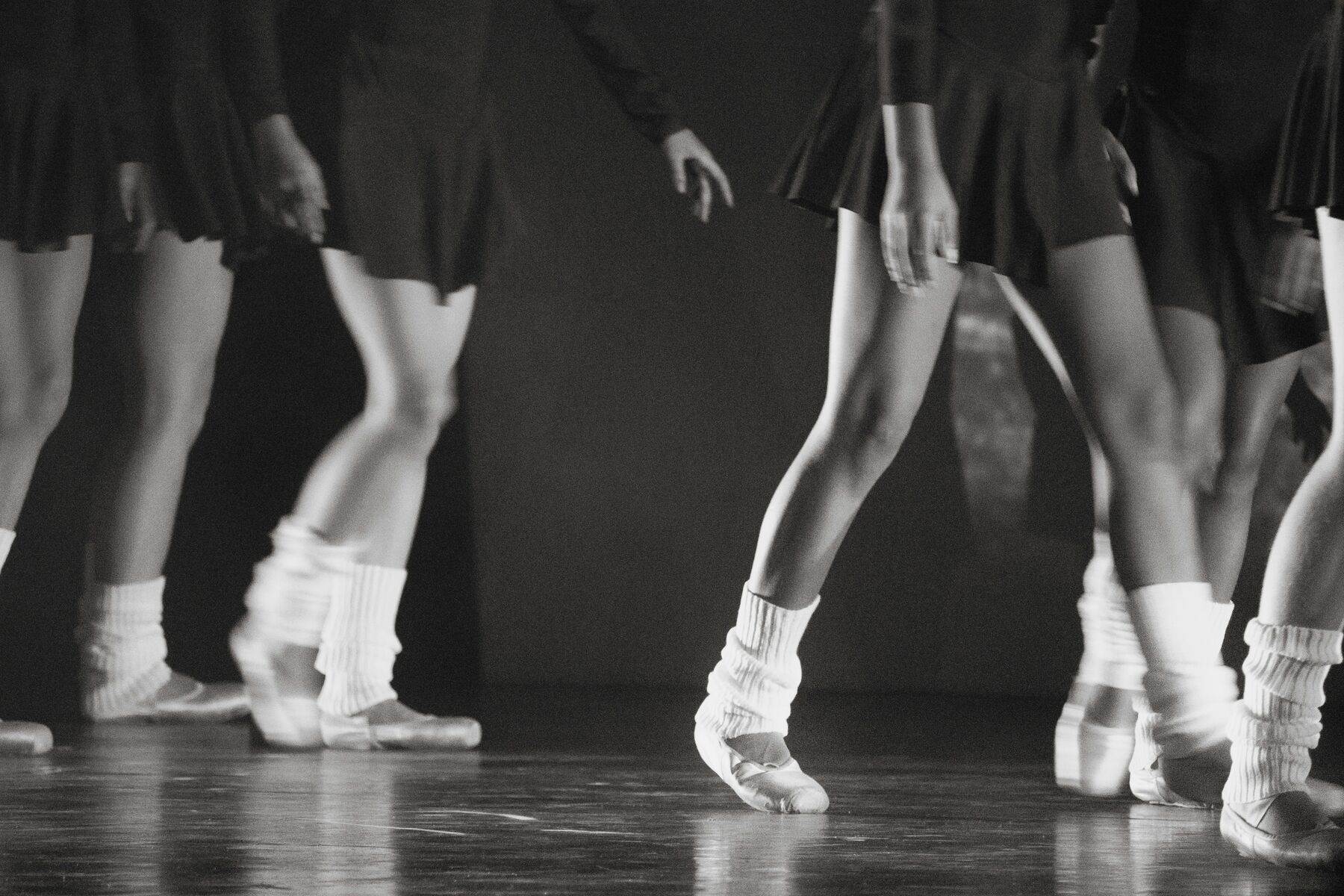 Dancers' legs in white socks and jazz shoes on a studio floor